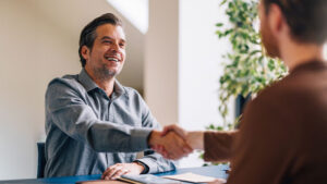 Two men shaking hands over a desk